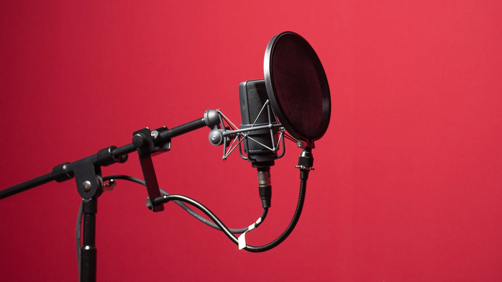 Photo d'un micro pour enregistrer la voix d'une personne sur fond rouge. Photo réalisée par l'atelier web astera sàrl.