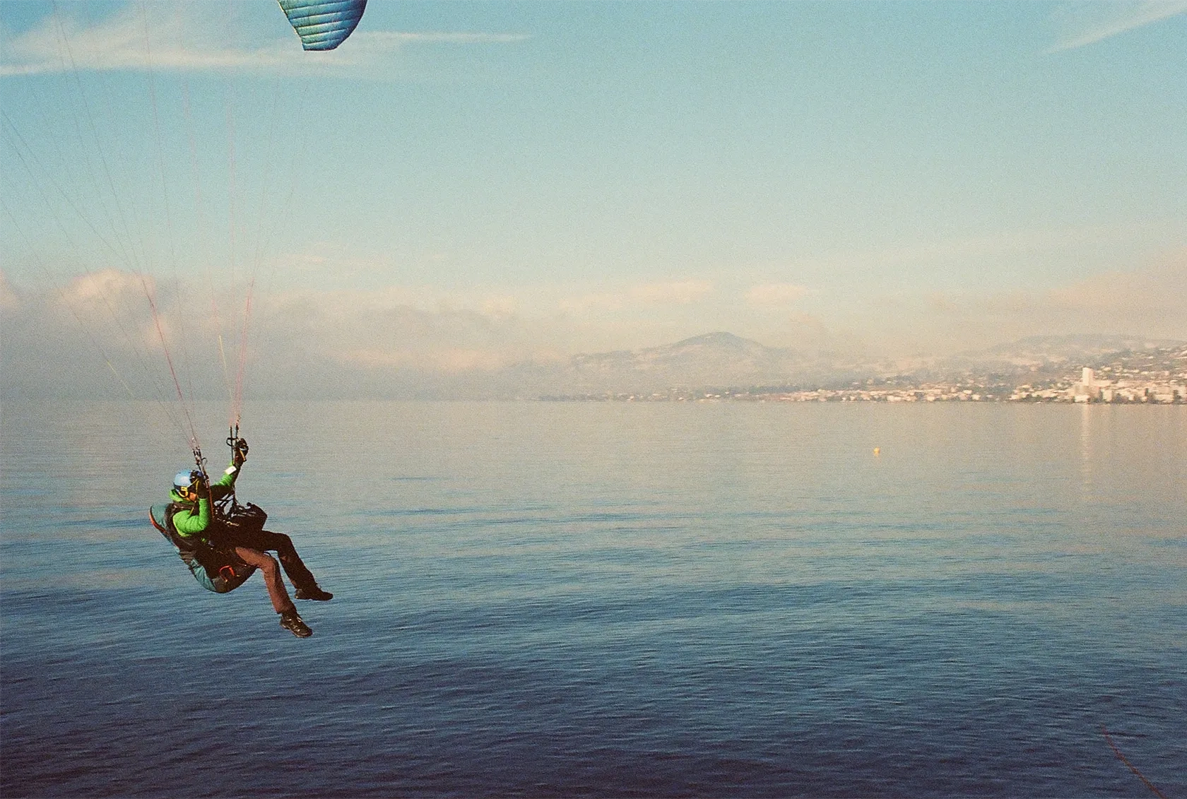 Image représentant un parapentiste volant très proche de l'eau au dessus d'un lac.